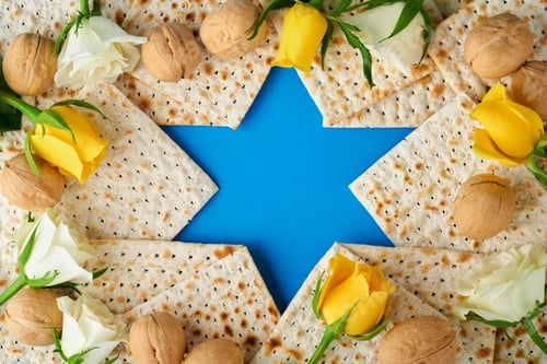 Preview: Passover celebration concept. Blue Star of David made from matzah, white and yellow roses, kippah an
