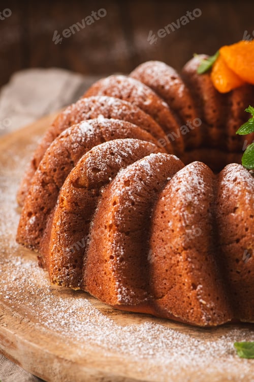 Preview: Freshly Baked Bundt Cake with Powdered Sugar and Apricot Garnish