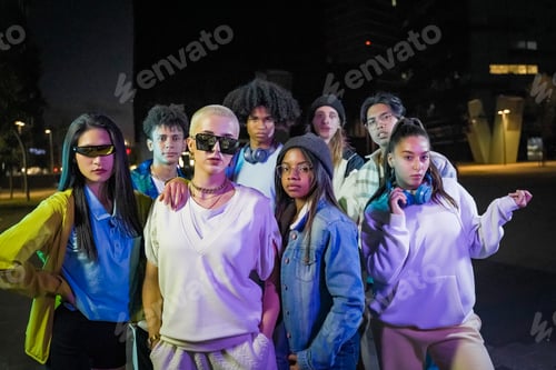 Preview: Group of young people with modern outfits in the street at night looking to the camera.