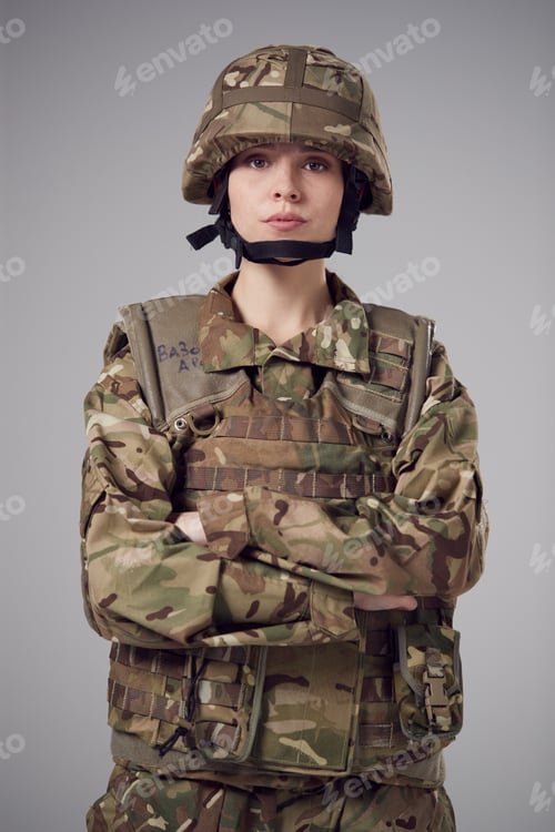 Preview: Studio Portrait Of Serious Young Female Soldier In Military Uniform Against Plain Background