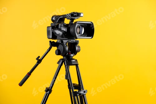 Vista previa: Modern video camera with tripod on yellow background, space for text