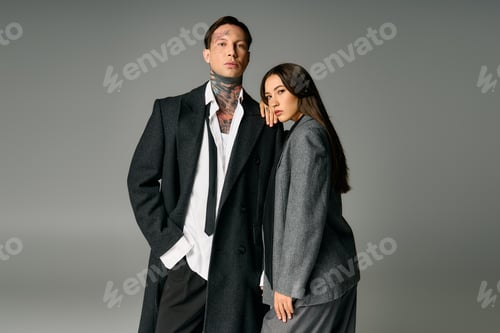 Preview: Young man and woman in stylish gray outfits striking a confident pose on a neutral backdrop