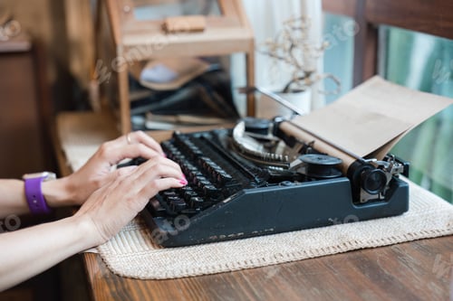 Preview: Hand of woman typing on old vintage typewriter with paper