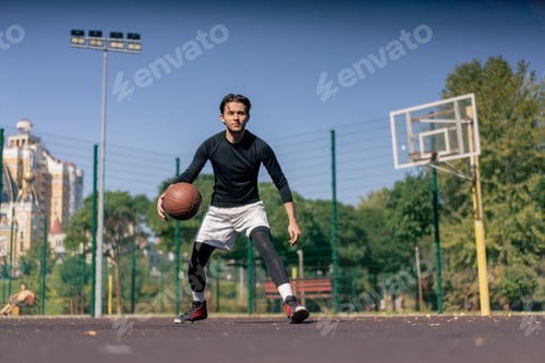 Preview: a sports ground basketball field active recreation guy in white shorts and black t-shirt plays