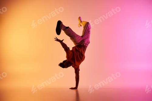 Preview: African american dancer performs handstand on gradient background