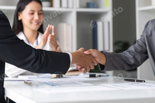 Preview: Businessmen Shaking Hands in Agreement at Modern Office with Colleague Applauding in Background