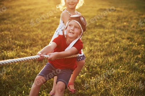 Preview: Boy and girl pulling a rope and playing tug of war at the park