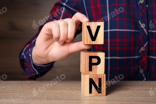 Preview: Woman making acronym VPN with cubes at wooden table, closeup