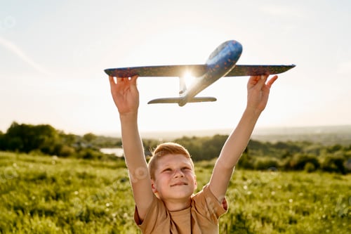 Preview: Close up of ginger boy playing toy airplane on the meadow