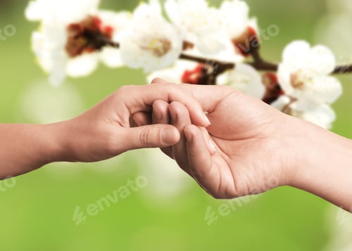 Preview: Man and woman holding hands against blooming tree branch, closeup