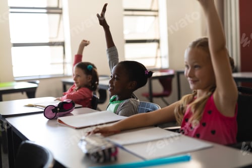 Preview: Side view of schoolgirls raising hand in classroom of elementary school