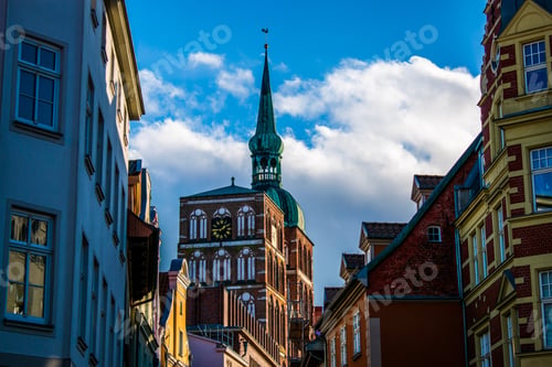 Preview: Low-angle shot of a clock tower from a narrow city street
