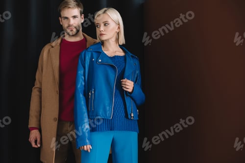 Preview: stylish couple in autumn outfits standing near curtain
