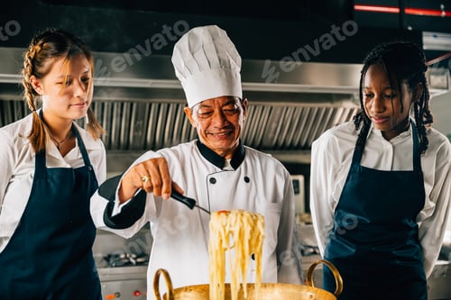 Preview: In kitchen chef mentors students. Schoolgirls cook ramen. Kids with teacher at stove. Smiling