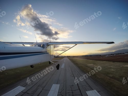 Preview: Small airplane taking off from a runway during a vibrant evening before sunset