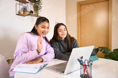 Preview: Teenage girls having video call on laptop at home