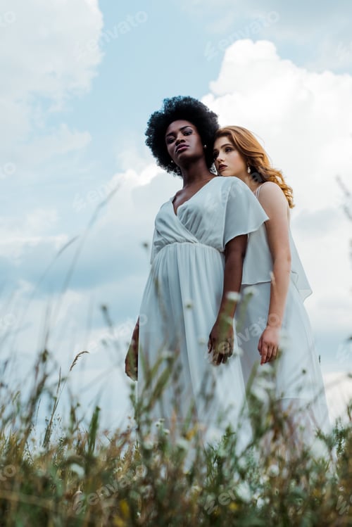 Preview: selective focus of redhead girl standing with african american woman against sky