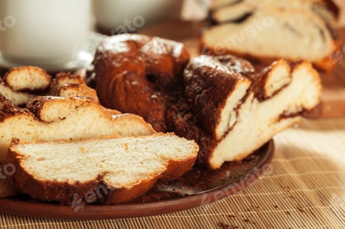 Preview: Baked bread sits on a plate with a cup nearby during morning hours at home