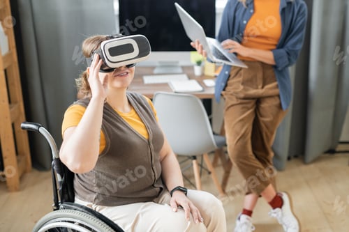 Preview: Disable businesswoman in vr headset sitting in wheelchair against busy colleague