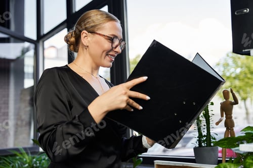 Preview: Young plus size woman joyfully working in a modern office setting surrounded by greenery