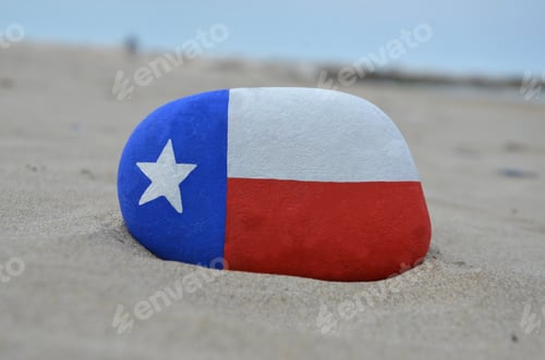 Preview: Texas flag painted on a stone over the sand
