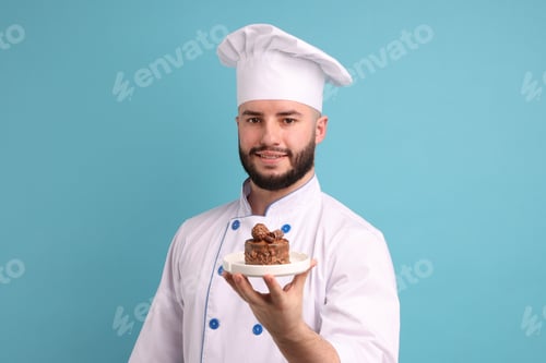 Preview: Happy confectioner in uniform holding delicious chocolate dessert on light blue background
