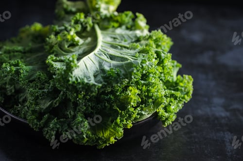 Preview: Fresh curly kale salad over dark rustic background.