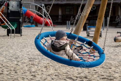 Preview: Boy swings on a spider web swing at a playground