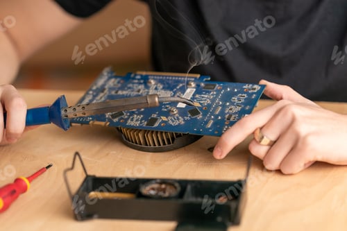 Preview: a young man solders a burnt-out microcircuit with a soldering iron