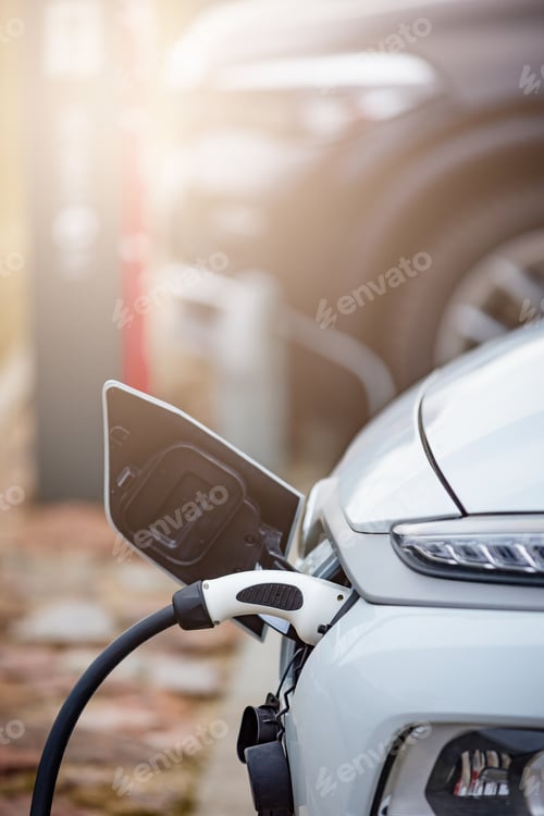 Preview: Selective focus shot of an electric car at a charging station with the power cable plugged in