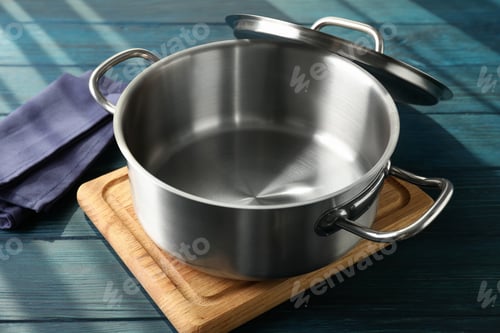 Preview: Empty metal pot on cutting board on wooden table