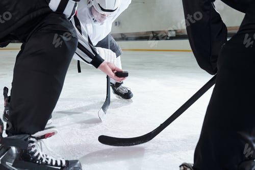 Preview: Hockey referee holding puck over ice rink while two rivals with sticks around