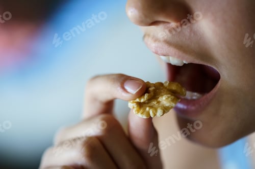 Preview: Unrecognizable girl with mouth open about to eat healthy walnut