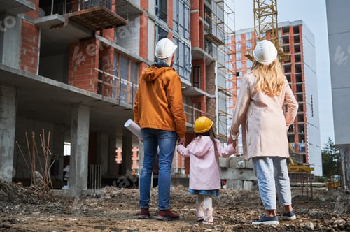 Preview: Family with child standing outdoors near building under construction.