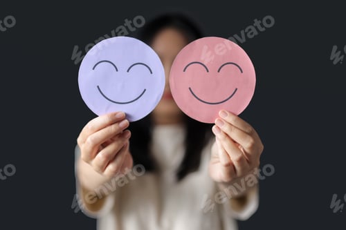 Preview: Female Hand Showing Two Colored Smiling Face on Dark Background. Expression of Positivity Concept.