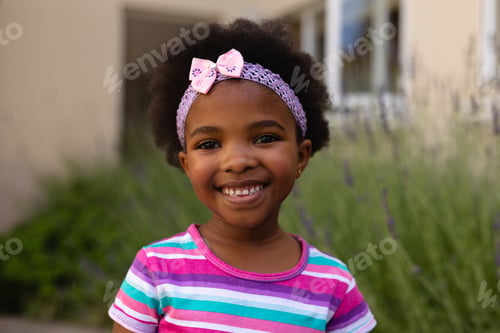 Preview: Portrait of smiling cute african american girl wearing headband and striped t-shirt