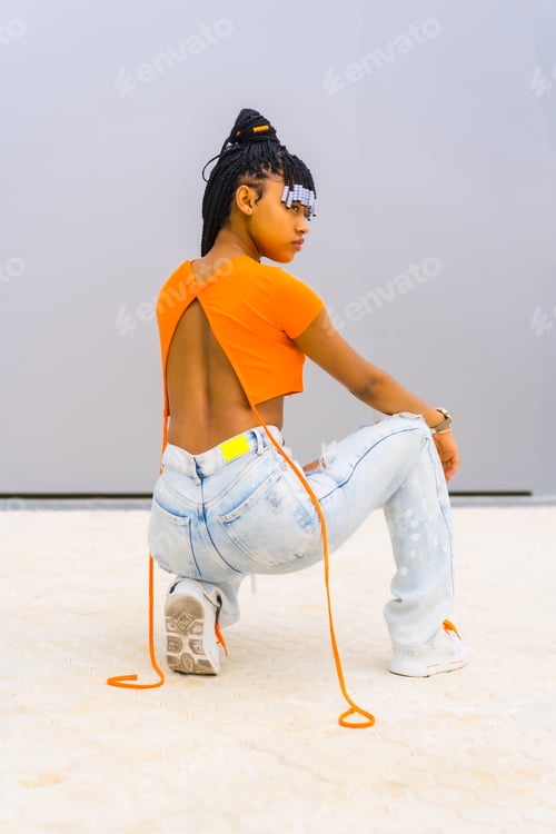 Preview: Black ethnic girl with orange t-shirt and cowboy pants. Posé with his back