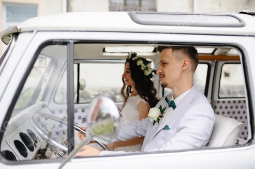 Preview: Hipster bride and groom are sitting behind the wheel of their retro bus.