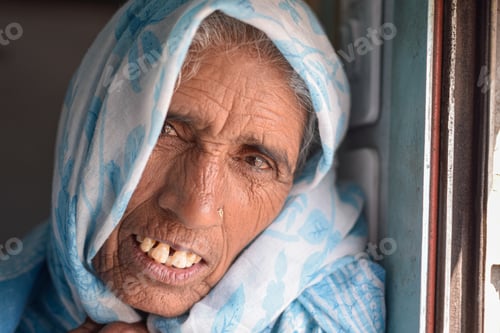 Preview: Elderly woman with beautiful face, wrinkles and blue sari looking to camera