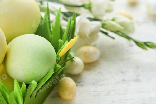 Preview: Happy Easter. Easter eggs and rabbit in green basket on white old wooden table with white and yellow