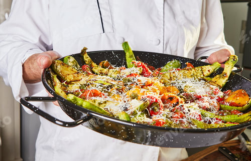 Preview: The chef holds vegetarian salad with baked peppers, zucchini and parmesan cheese
