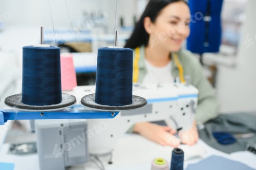 Preview: Young woman working as seamstress in clothing factory.
