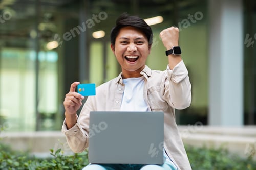 Preview: Happy young asian man use laptop, hold credit bank card