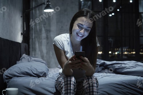 Preview: Woman Smiling and Using Mobile Phone in Bedroom