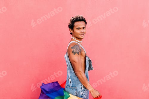 Preview: Handsome guy posing outdoors with LGBT flag and looking at camera