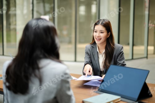 Preview: Business professionals discussing strategy during a modern office meeting with laptop and tablet,
