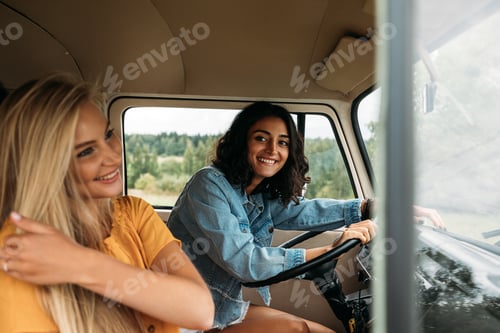 Preview: Young woman sitting on a driver seat in camper van. Two women in a car during a road trip.