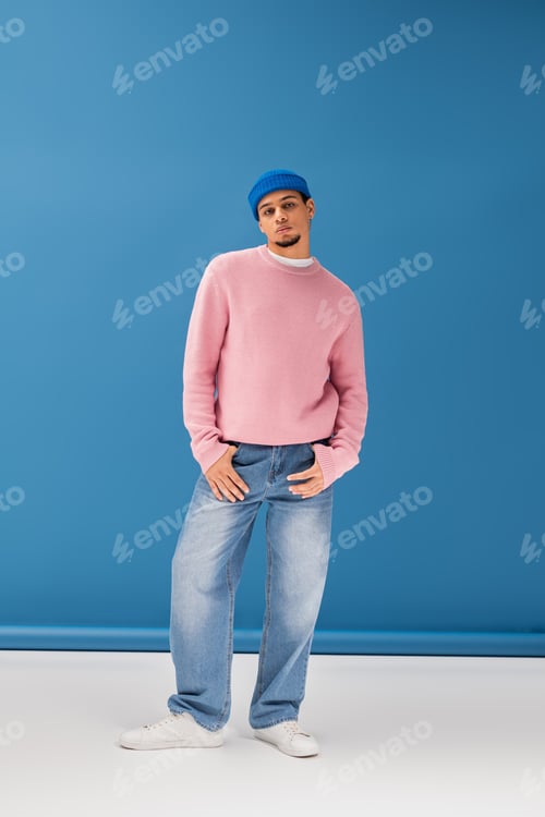 Preview: Handsome young man poses stylishly in trendy attire against a bright blue backdrop
