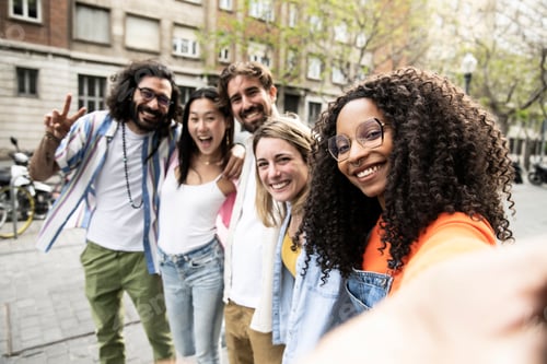 Preview: Multiracial group of friends laughing and taking a selfie in the street.Cheerful diverse group of