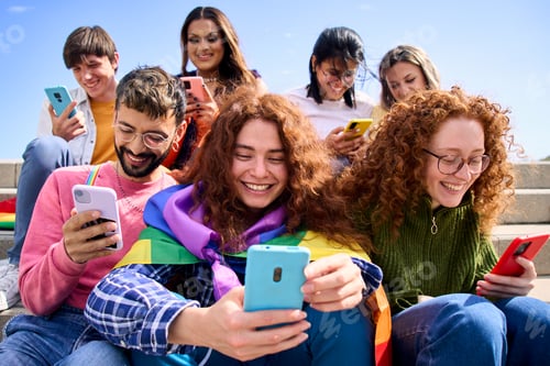 Preview: Smiling young friends using mobile phone celebrating gay pride festival day together